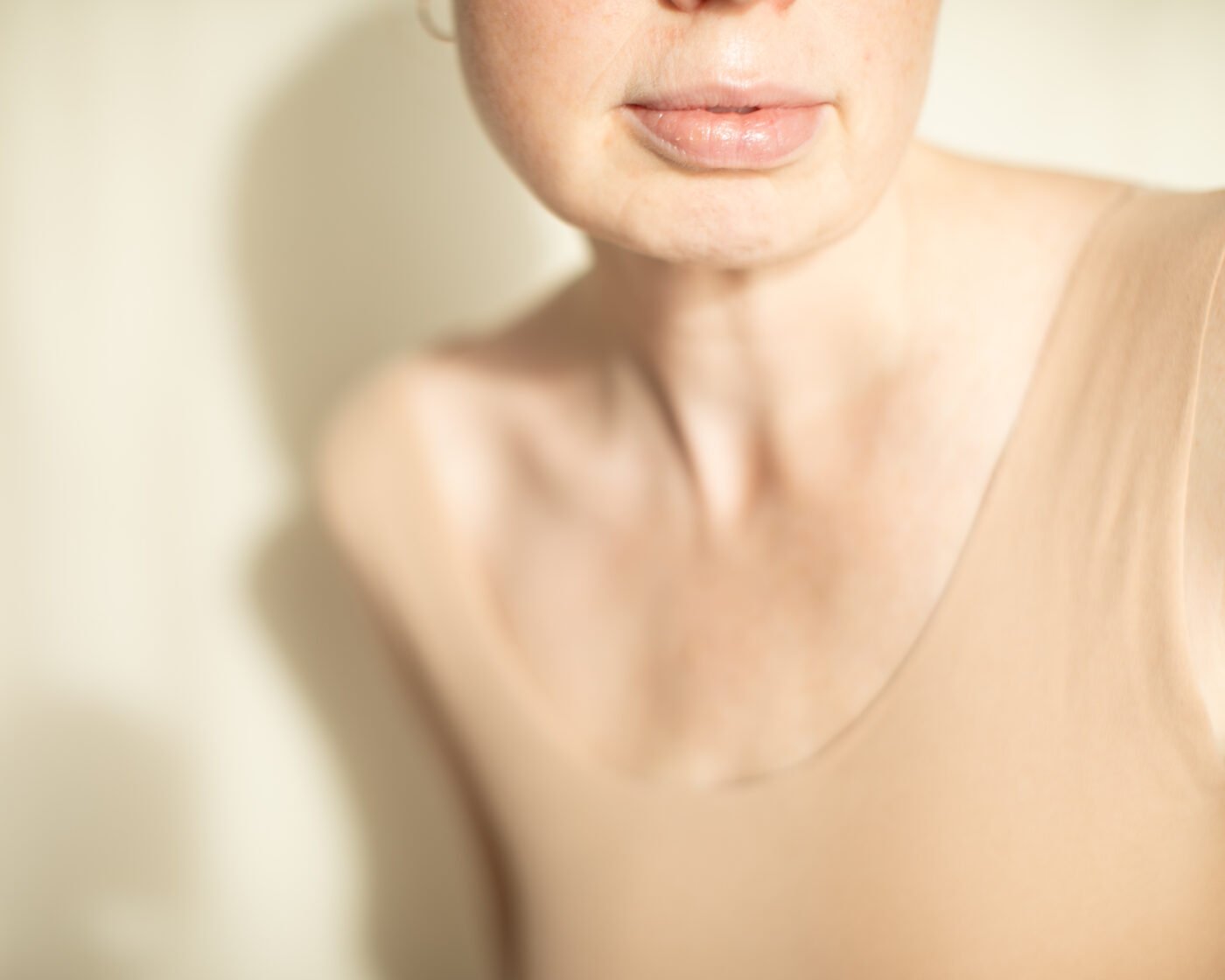 Close-up of lips and jaw in soft natural light, minimal skincare styling