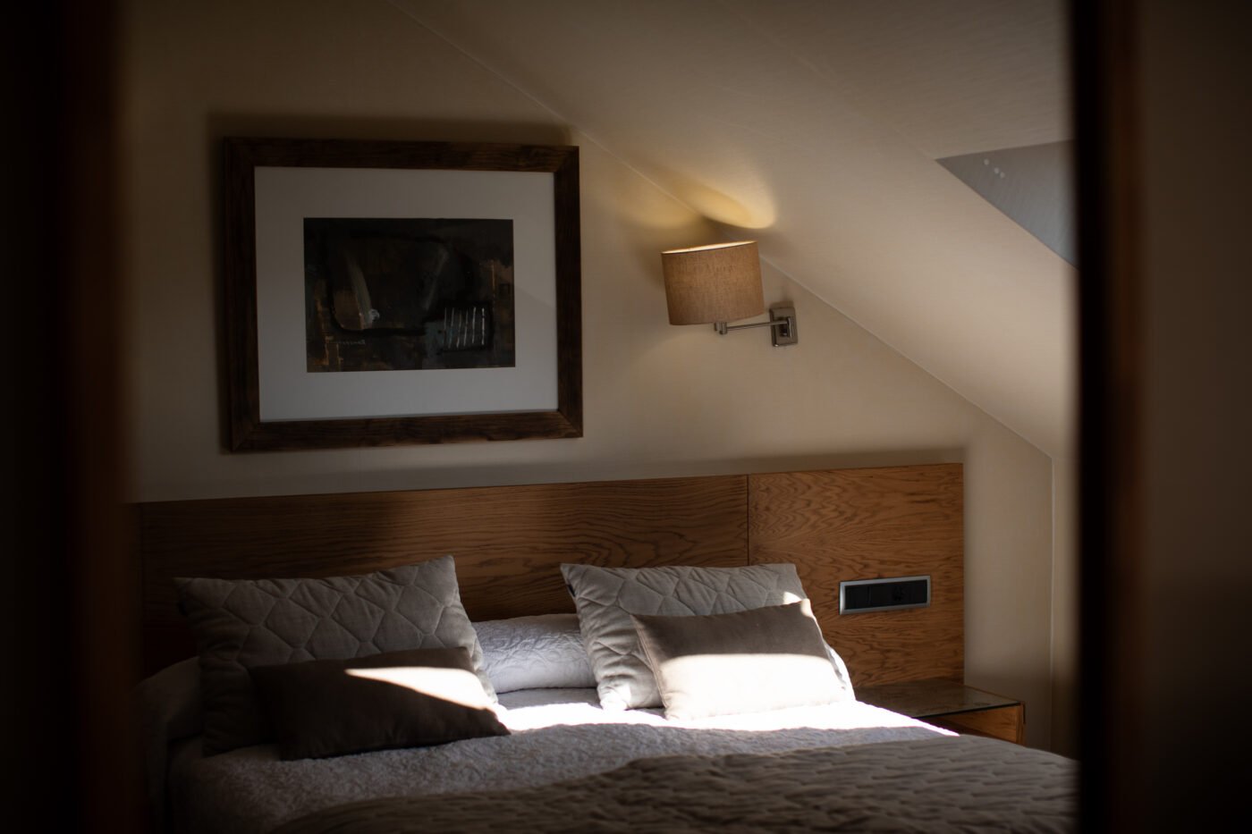 Sunlit bedroom interior with a framed print above the bed
