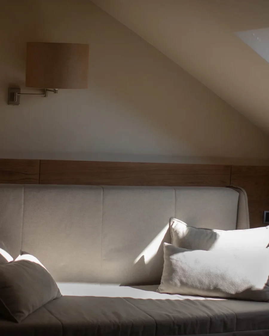 Sunlit daybed with linen pillows, seen through an open attic doorway
