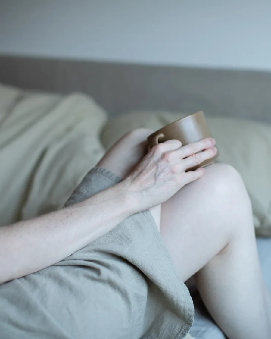Woman sitting with knees drawn up, holding a ceramic mug