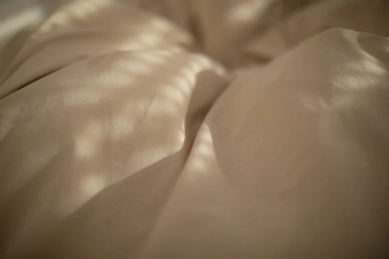 Close-up of rumpled bedsheets with dappled light