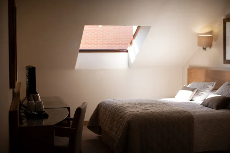 Attic hotel room with skylight, writing desk and bed