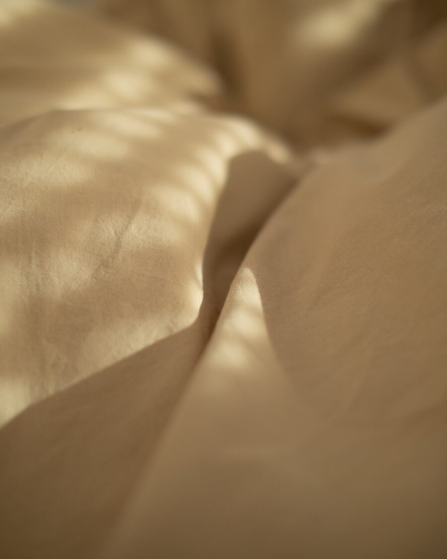 Close-up of rumpled linen bedding with dappled morning light